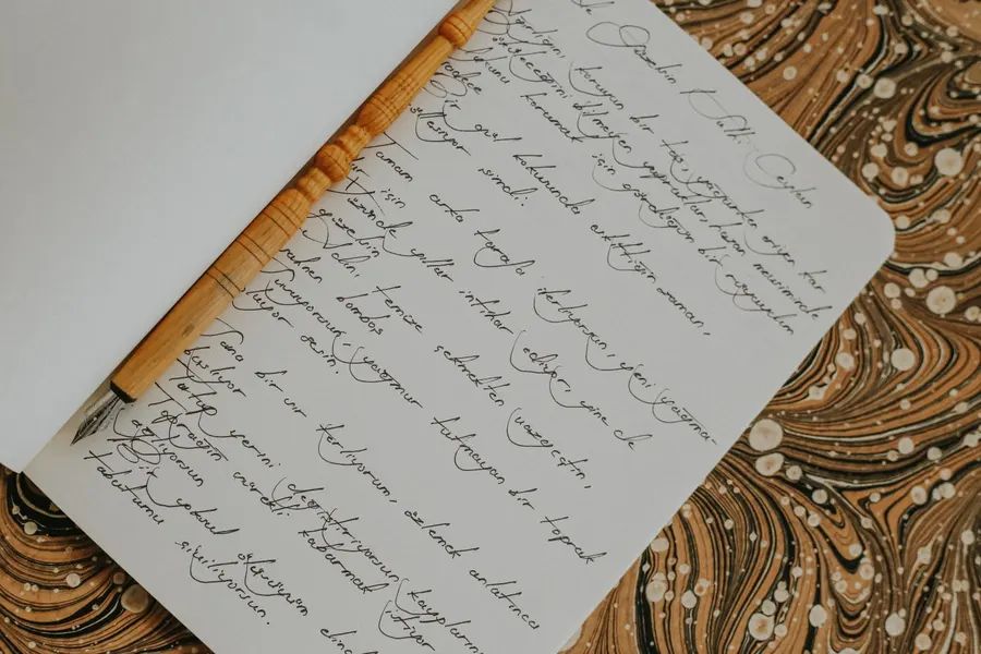 A pen resting on a page of handwritten verse