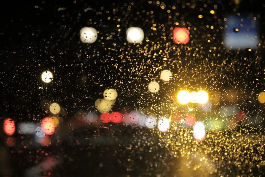 A rain-streaked window over a city at night